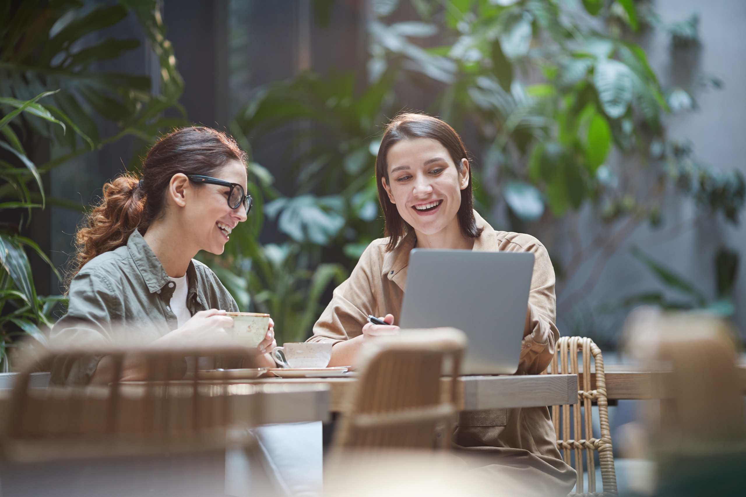 Two Cheerful Businesswomen Working in Cafe